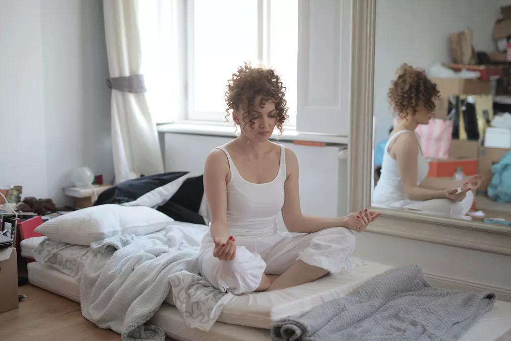 vrouw zittend in yoga positie op matras voor spiegel