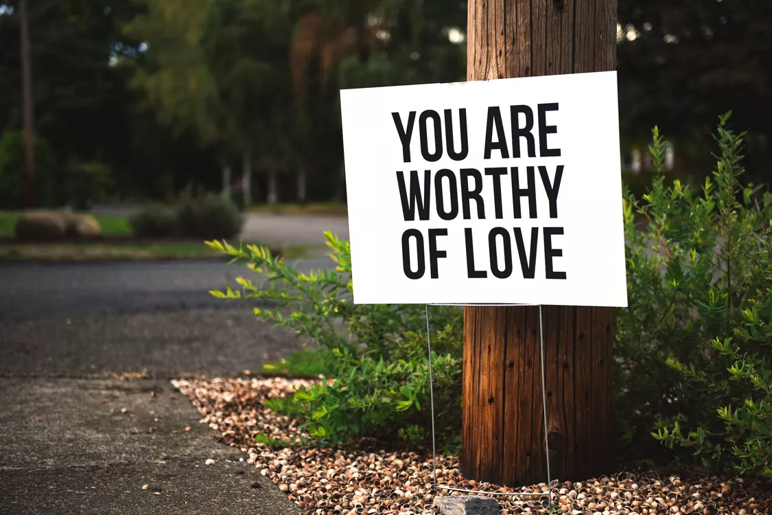 bord tekst buiten tegen een boom met tekst You are worthy of love