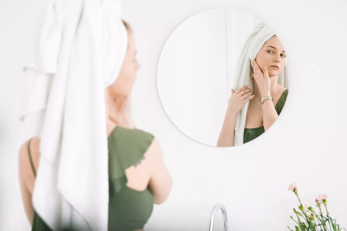 spiegelbeeld van vrouw met witte handdoek op hoofd 