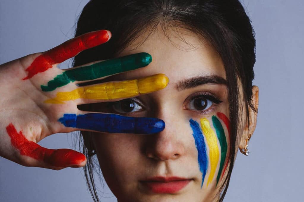 vrouwen ogen met vingers in groen geel blauw en rood geverfd voor gezicht