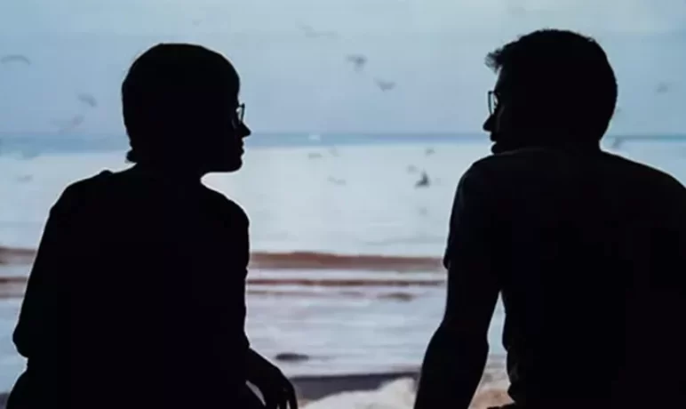 silhouet van man en vrouw pratend tegen elkaar in een open raam, uitzicht over het water