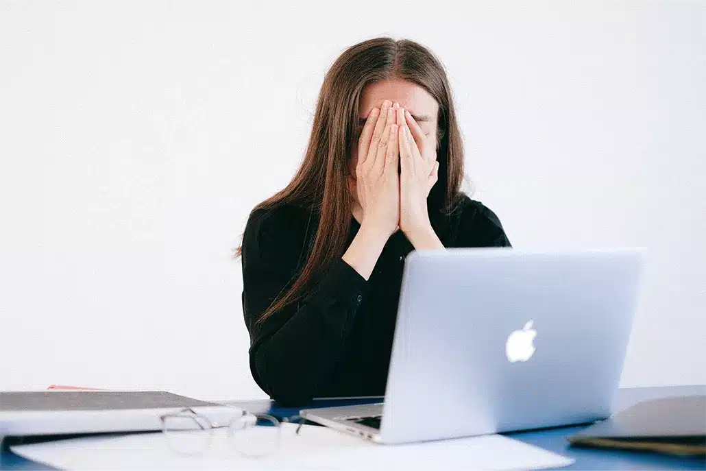 vrouw voor laptop met beiden handen voor gezicht