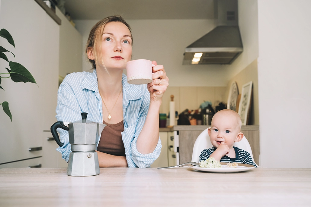 moeder die een kop koffie drinkt naast een baby