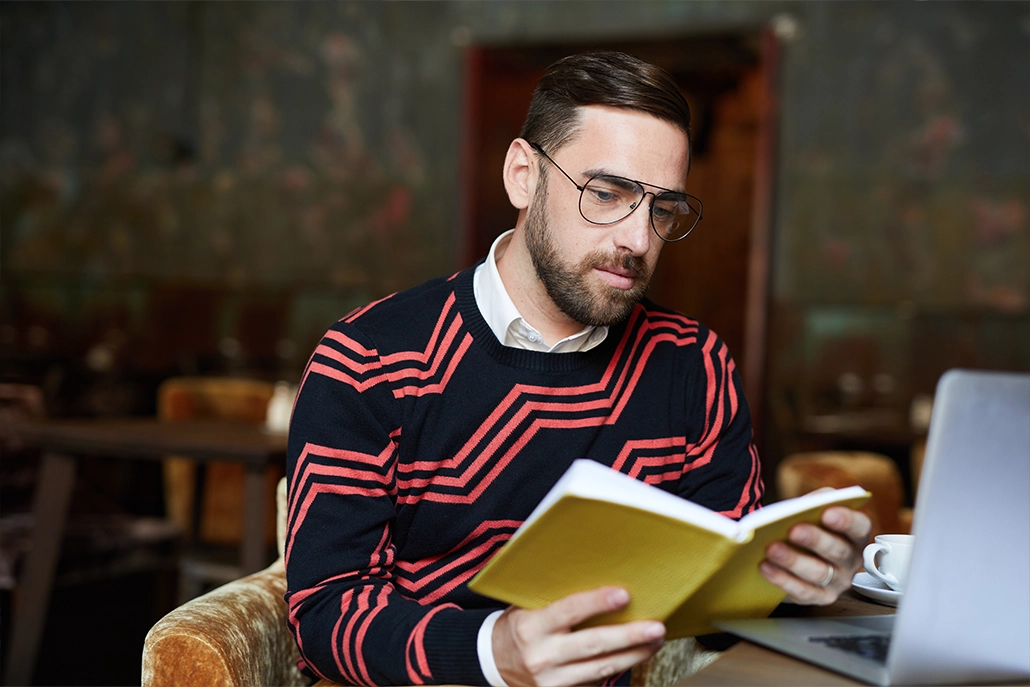 Man met een bril die een boek leest